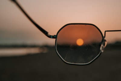 日落时海滩上的黑框太阳镜